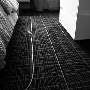 photograph of a section of carpeted floor in the artist's bedroom, covered in lines of blue tape used to form the labyrinth